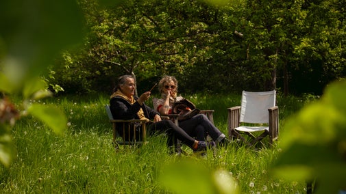 Visitors sat in deckchairs in the sunny orchard at Calke Abbey during a creative workshop